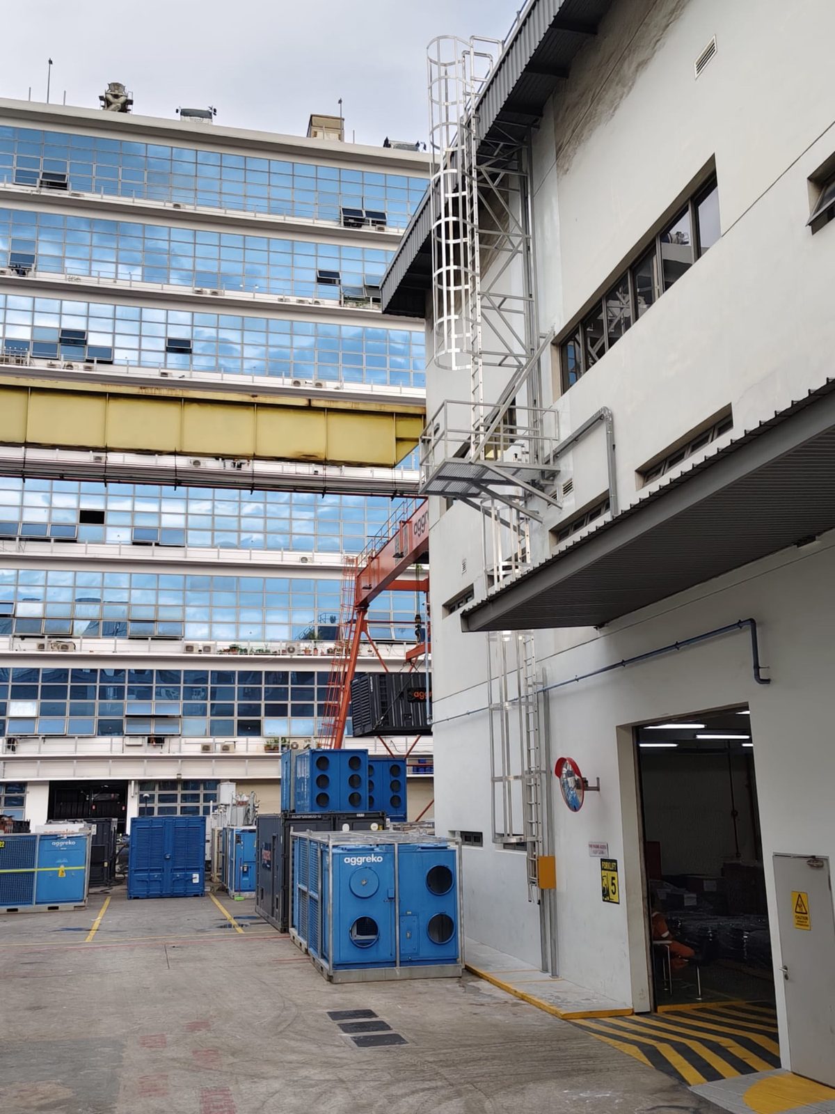 Wider yard view of the Buroh Street cat ladder installation showing the lower flight, intermediate platform and upper flight against the building facade
