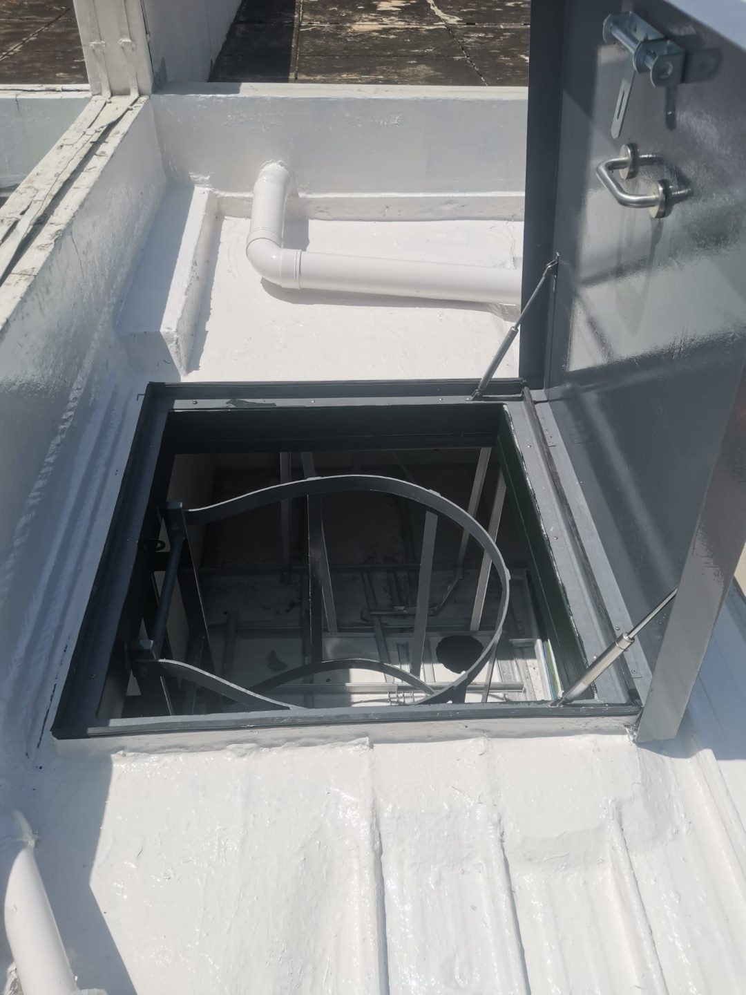 Open roof access hatch at Tuas View showing the ladder structure below and gas-strut stays